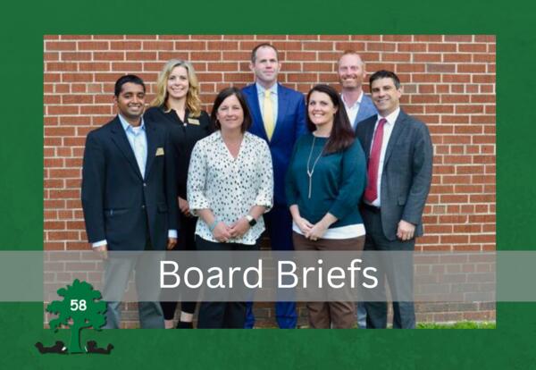 Photo of 7 board members standing against brick wall