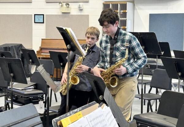 Two male students playing saxaphones at music stand