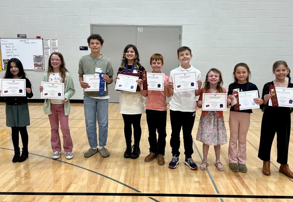 Line of students proudly holding art competition certificates