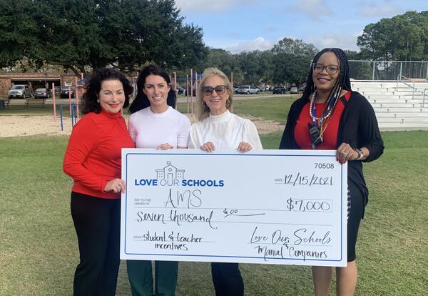 Brendy White, principal of Acadian Middle School, receiving check from Missy Manuel with Manuel Companies.