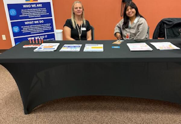 Two women sitting at a table for the ND Full Service Community Schools smiling