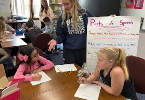 DSU Student educating two students with a poster on the "Parts of Speech"
