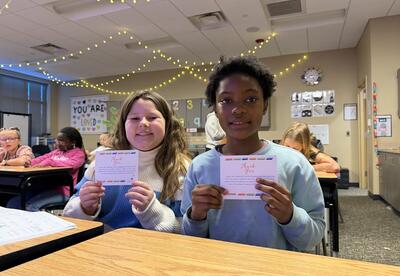 Two female students posing with their postcards