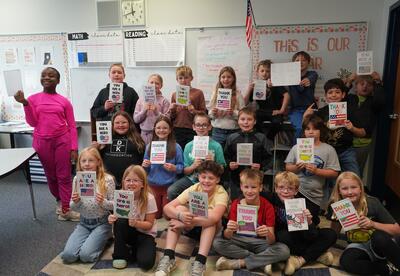 A third grade classroom holds up their cards for veterans