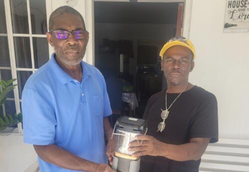 Substitute teacher, Denisford Kerr in Jamaica giving a solar lamp to man who lost electricity