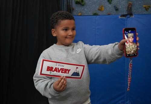 Photo of student at posed with bravery card and a phone photo of his military brother