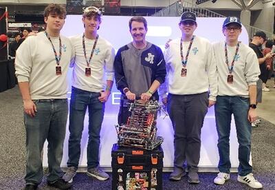Photo of 4 students with coach at World Robotics Competition