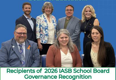 Group photo of the River Trails School District 26 Board of Education members smiling in front of a blue background. Text above reads "Congratulations, River Trails School District 26 Board of Education!" and text below reads "Recipients of 2026 IASB Scho