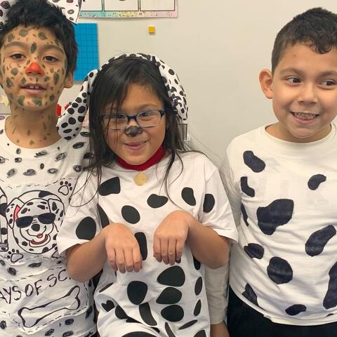Three students smiling, dressed as Dalmatians