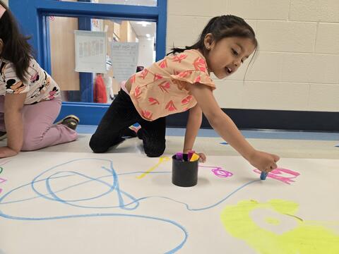Girl painting on large sheet of paper