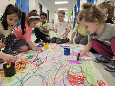 Several students working together on an art project in the hallway