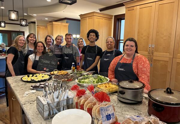 A group of volunteers stand around a kitchen island with the food they prepared at the Ronald McDonald House.