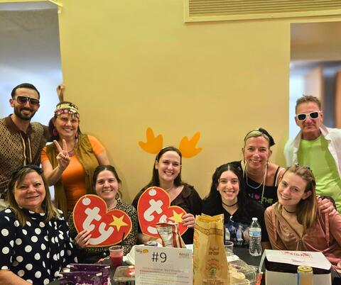 Group in themed costumes smile with a yellow wall in the background