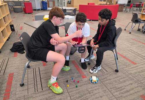 Three students coding robots on the iPad in the Media Center