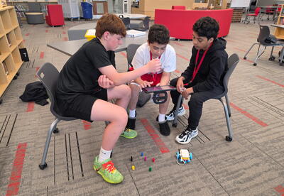 Three students coding robots on the iPad in the Media Center
