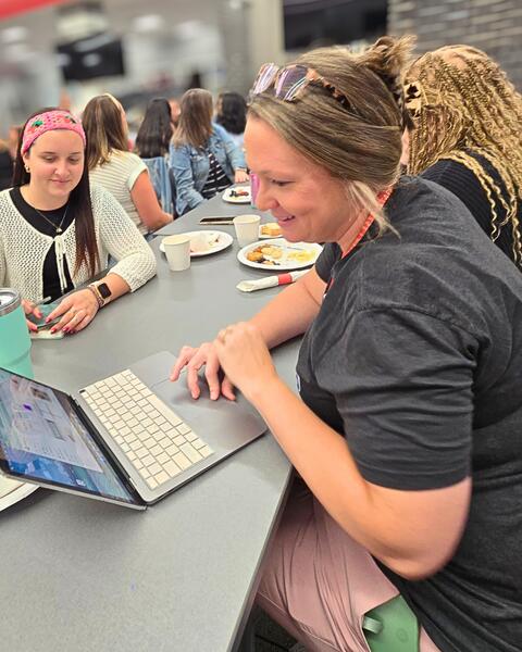 Two people having a conversation over a laptop.