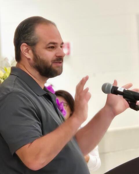 Man speaking with a microphone at a podium.