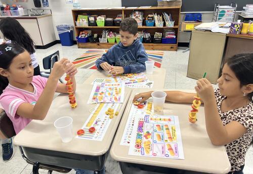 Students working a project resembling a backbone in a classroom setting