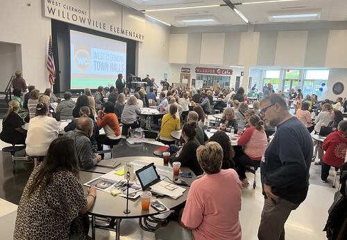 A large room at Willowville Elementary with many people sitting at tables