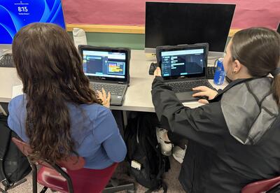 Here is a photo of two students working on Chromebooks to customize code for their robotics project