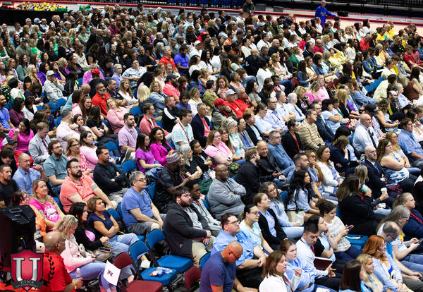 Photo of many teachers and staff sitting in folding chairs in a crowd