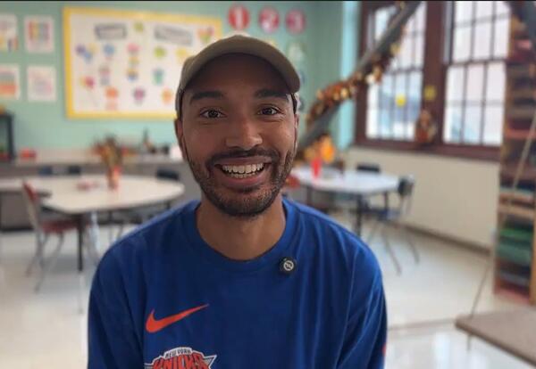 Man smiling in classroom wearing cap