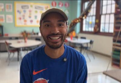 Man smiling in classroom wearing cap