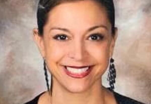 Woman smiling wearing long earrings and red lipstick in school photo