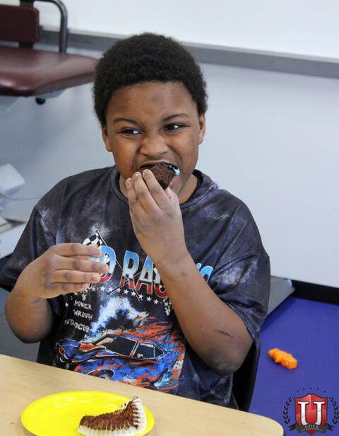 Student biting into chocolate cupcake