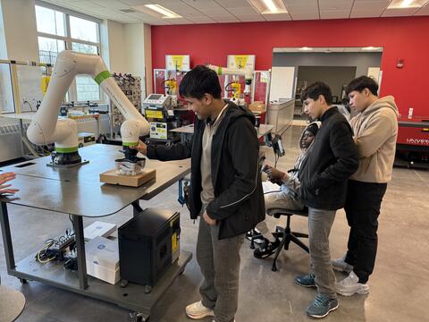 Students watching while one student uses machinery