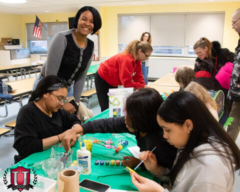 Staff smiling while students work on project