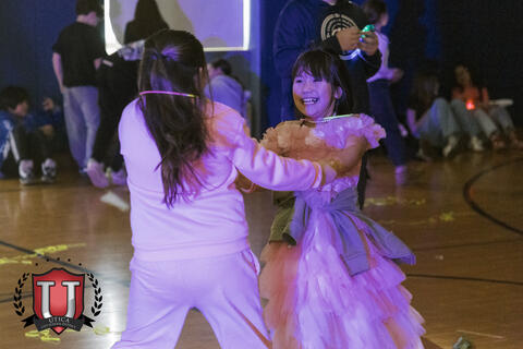 Two students dancing around holding arms happily