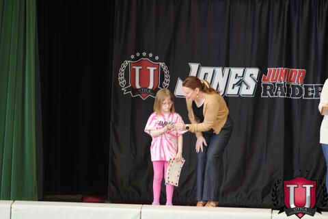 Teacher bends over to give award to student