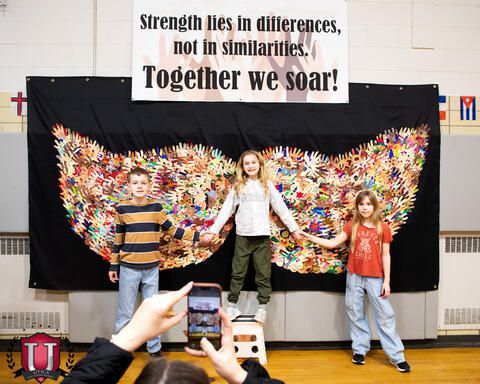 Students posing under a great display of butterfly wings