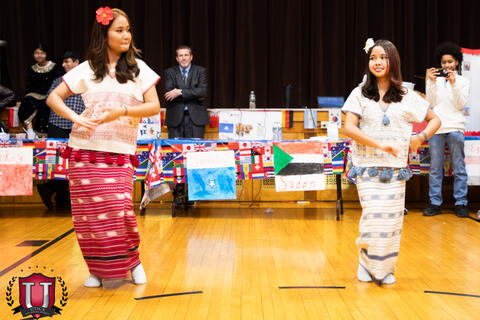 Two students dancing across from each other to a represent a cultural dance