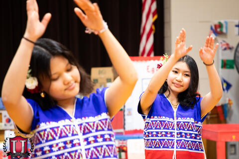 Students raise their arms during dance