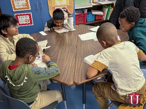 Students reading to each other across the table