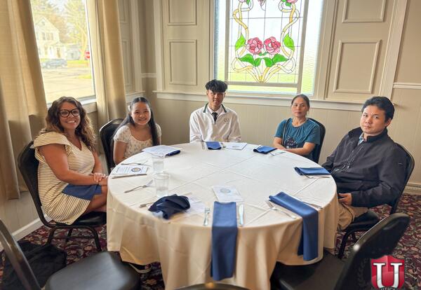 Students sitting at a table waiting to receive their awards