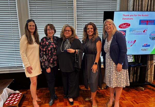 Five women standing together celebrating the award