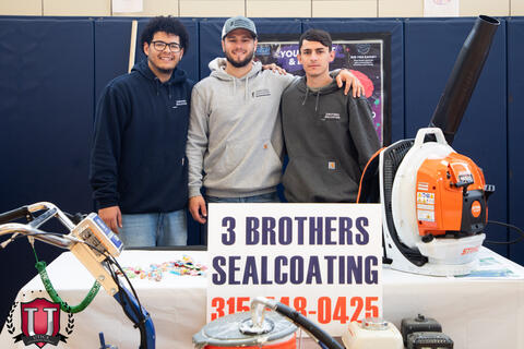 Three workers standing behind their poster