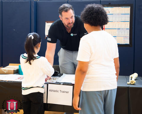 Students engaging with the athletic trainer and his table