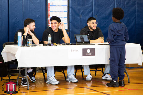 Students talking to the group behind the barber table