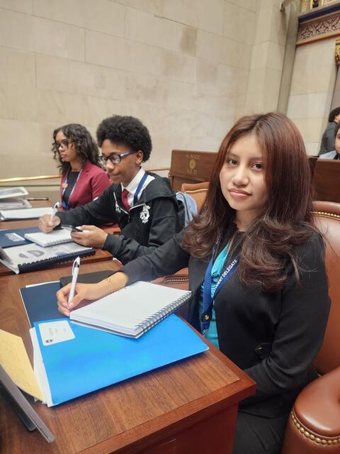 Students smiling while doing some work in their mock assembly