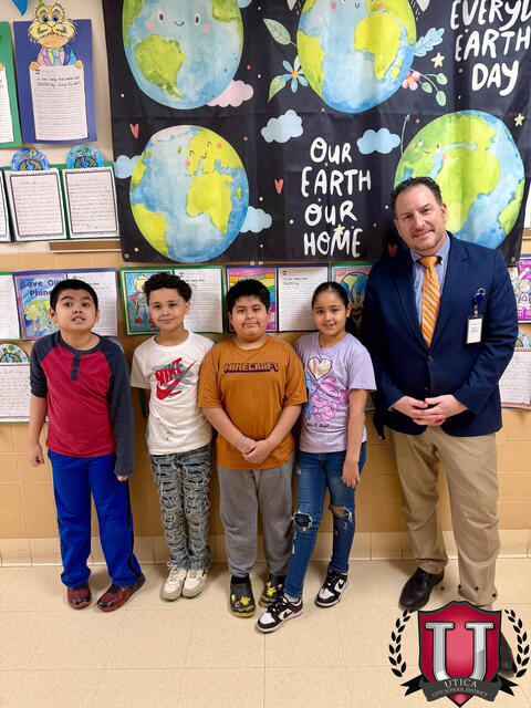 Teacher posing with some students around the Earth Day poster