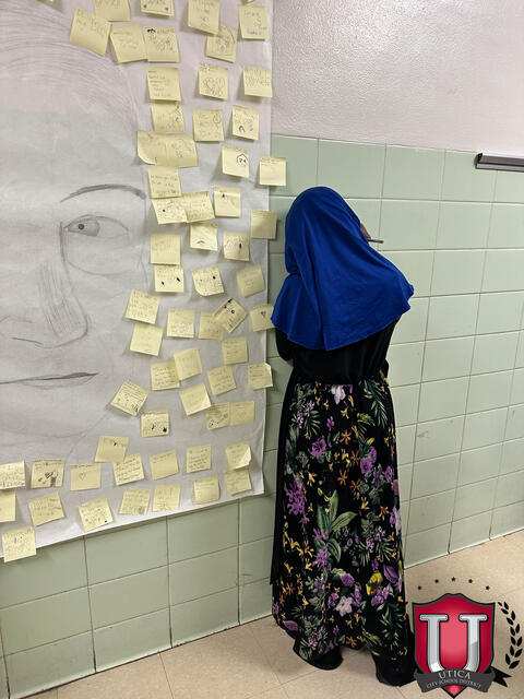 A student putting a post it note on the wall