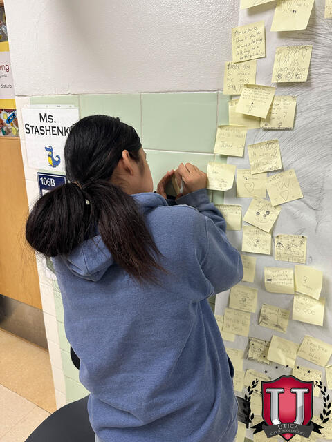 A close up of a student writing a post it note