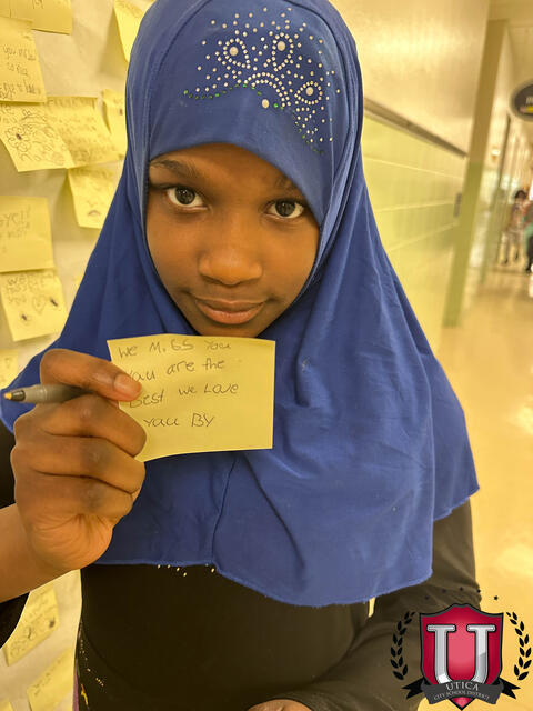 A student showing off her post it note for Lou