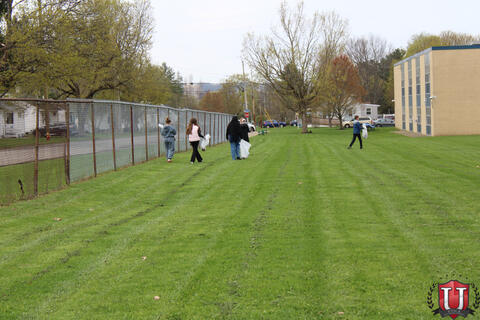 Students alongside a fence looking for trash