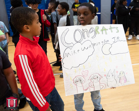 A student showing off his poster to another student
