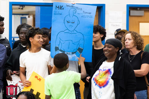 Students smiling while showing off their poster to mike